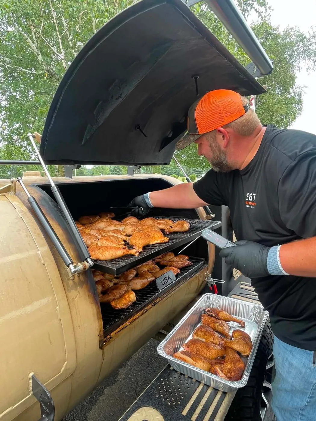 Pitmaster checking chicken temperatures on the offset smoker